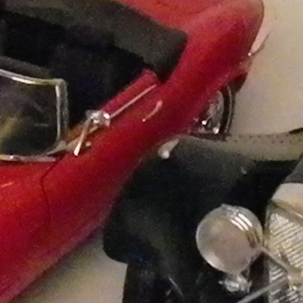 Close-up of a damaged model car with broken parts.