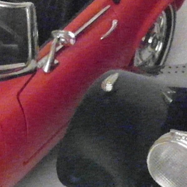 Close-up photo of a vintage red car and black leather case.