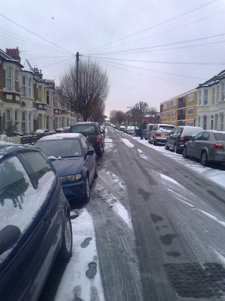 Snow-covered residential street with parked cars