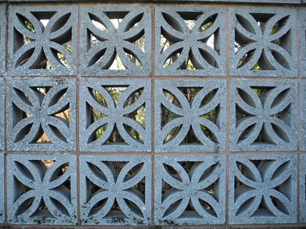Decorative concrete block wall with foliage in the background.