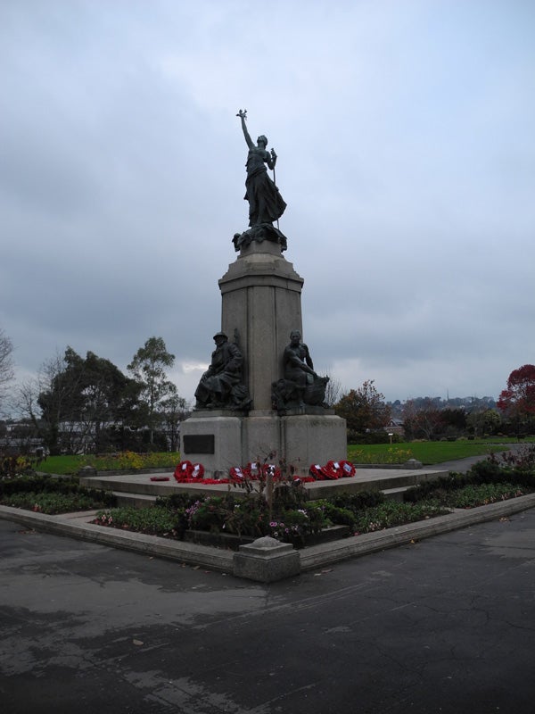 War memorial statue on cloudy day with wreaths