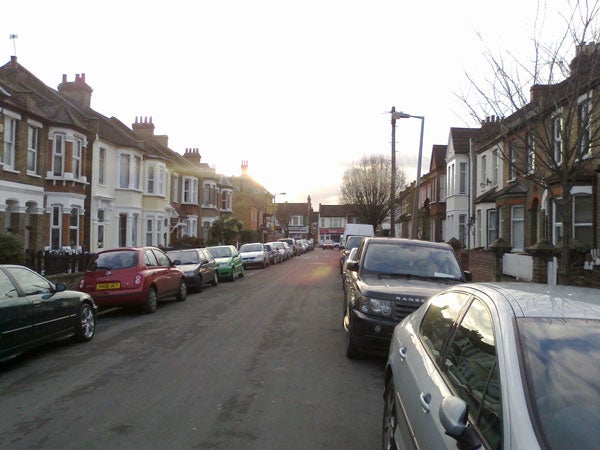 Street view at sunset with parked cars on both sides