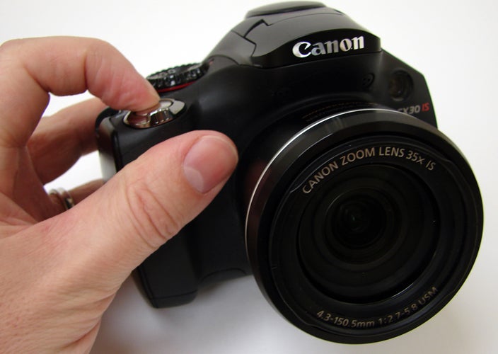 Hand holding Canon PowerShot SX30 IS camera.