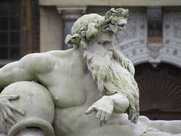 Statue of a reclining bearded figure with greenery on head