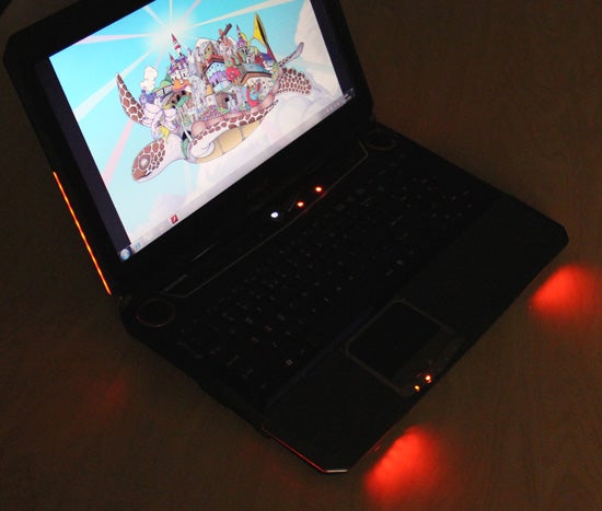 MSI GT680 gaming laptop with red backlight on desk.