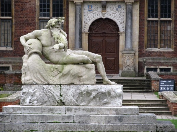 Stone statue of a reclining figure in front of a building.