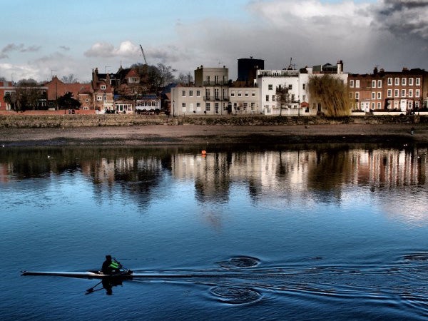 Rowing on calm water with town reflected in background.