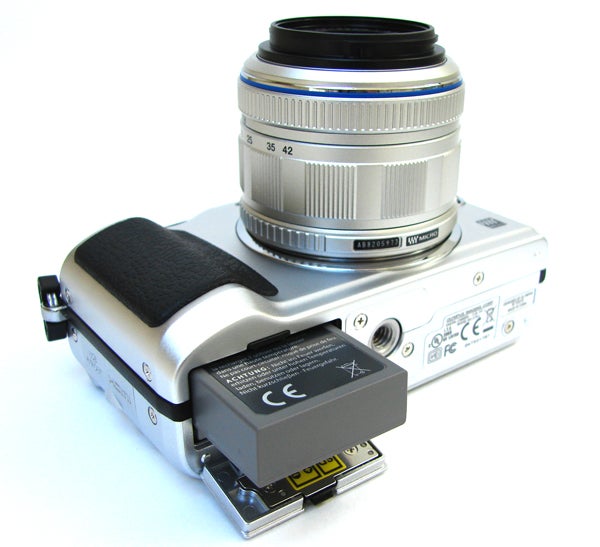 Olympus E-PL2 camera with lens and open battery compartment.