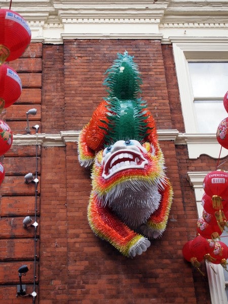 Colorful dragon decoration on brick wall with red lanterns
