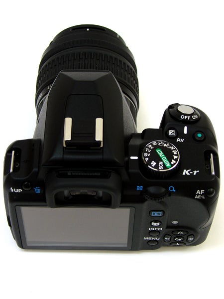 Pentax K-r DSLR camera with zoom lens on white background.