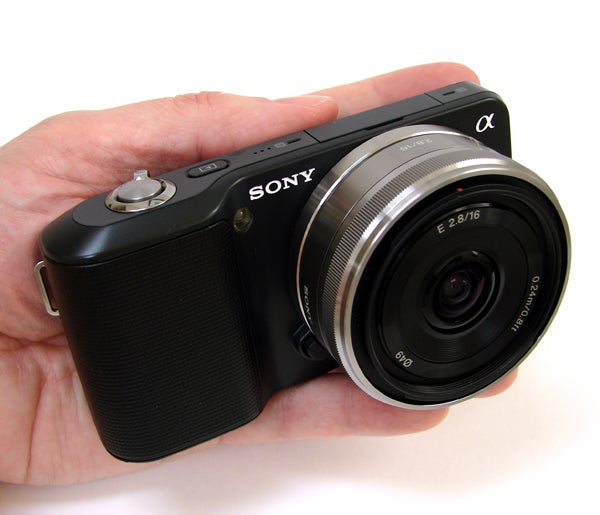Hand holding Sony Alpha NEX-3 camera with lens attached