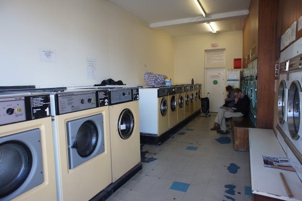 Interior of a laundromat with rows of washing machines and a sitting person.