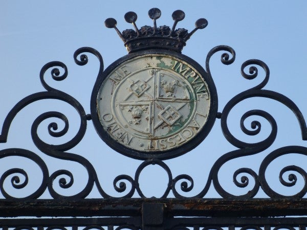 Ornate gate crest captured in clear detail against a blue sky.