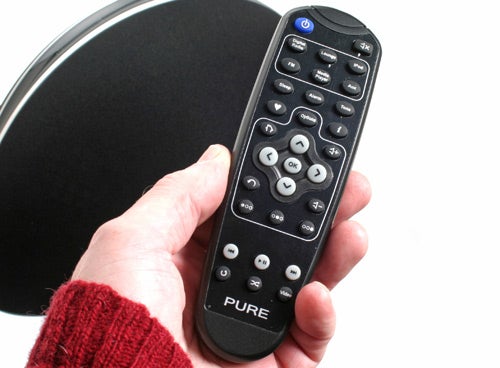 Hand holding a Pure Contour remote with device in background.