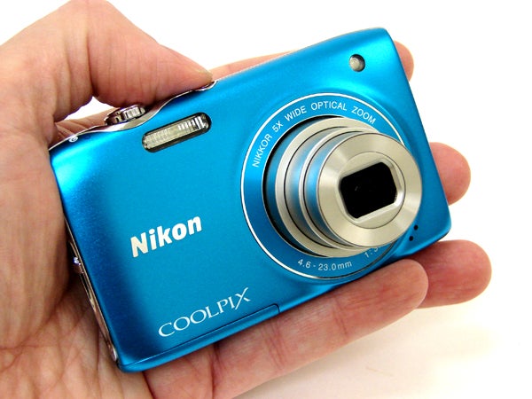 Hand holding blue Nikon Coolpix S3100 camera.
