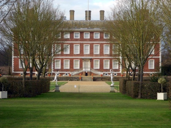 Photo of a stately brick mansion with manicured lawn and trees.