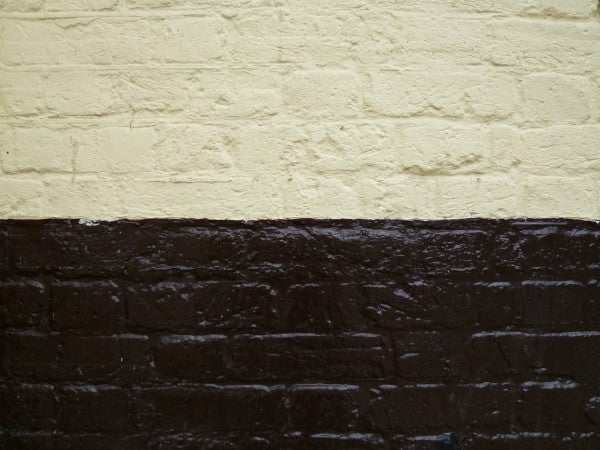 Textured cream wall meeting a dark brown brick base.