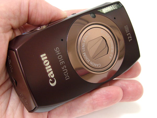 Hand holding a Canon IXUS 310 HS digital camera.