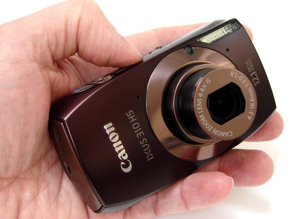 Hand holding a Canon IXUS 310 camera.