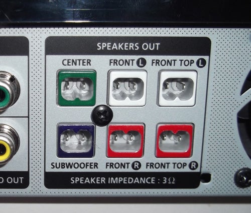 Close-up of Samsung HT-D6750W speaker output terminals.Clear speaker wires with red connectors.