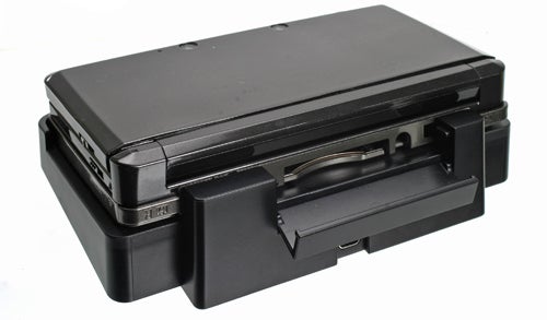 Black Nintendo 3DS console closed with charging cradle.