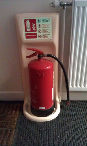 Fire extinguisher mounted on wall near radiator.Fire extinguisher and stand in a corner of a room.