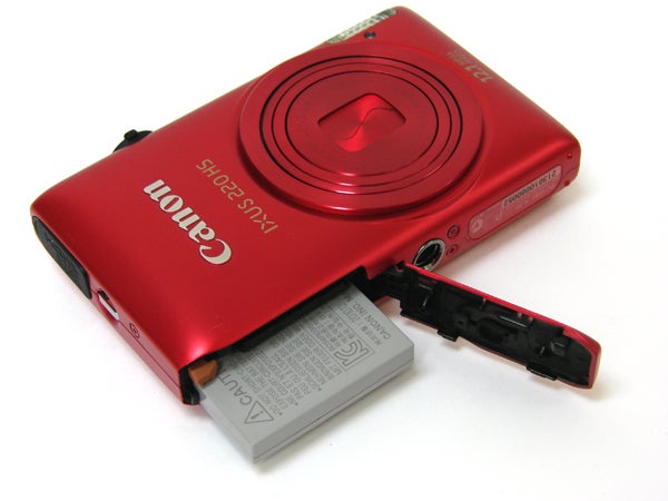 Red Canon IXUS 220 HS camera with battery compartment open.