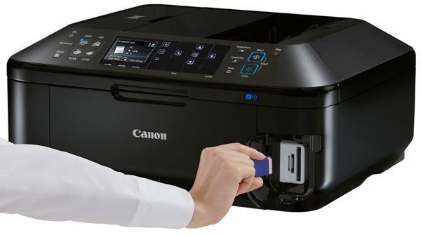 Hand inserting ink cartridge into Canon PIXMA MX885 printer.