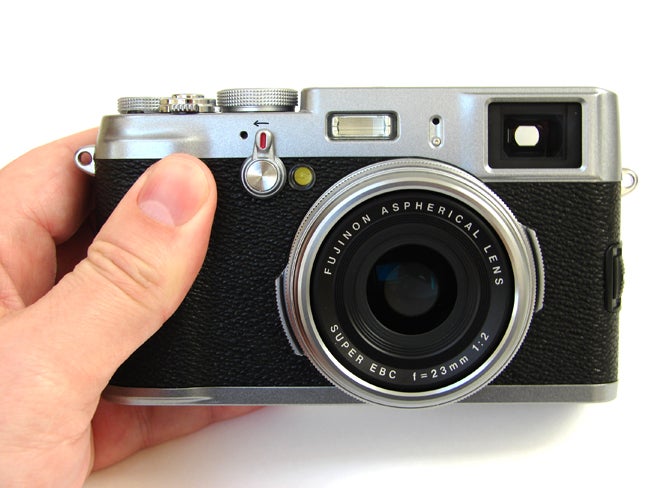 Hand holding a Fujifilm Finepix X100 camera.