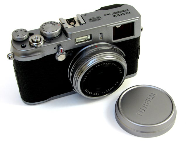 Fujifilm Finepix X100 camera with lens cap beside it.