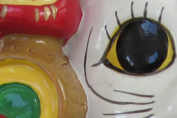 Close-up of colorful ceramic figurine's eye and mouth.