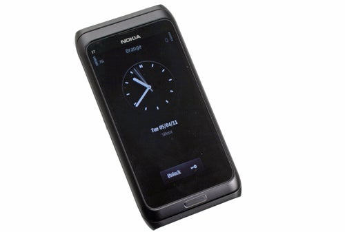 Nokia E7 smartphone with clock display on screen.