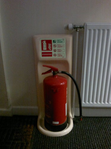 Fire extinguisher mounted on wall next to a radiator.