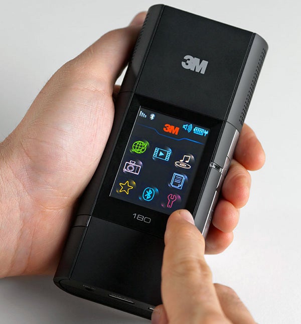 Hand holding 3M MP180 pocket projector displaying colorful icons.