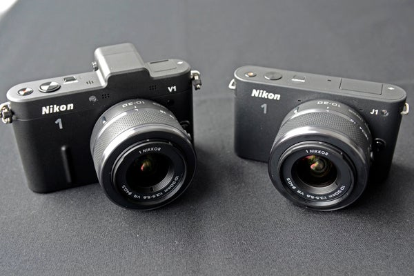 Nikon 1 V1 and J1 cameras side by side on a table.