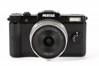 Pentax Q mirrorless camera with lens on white background.