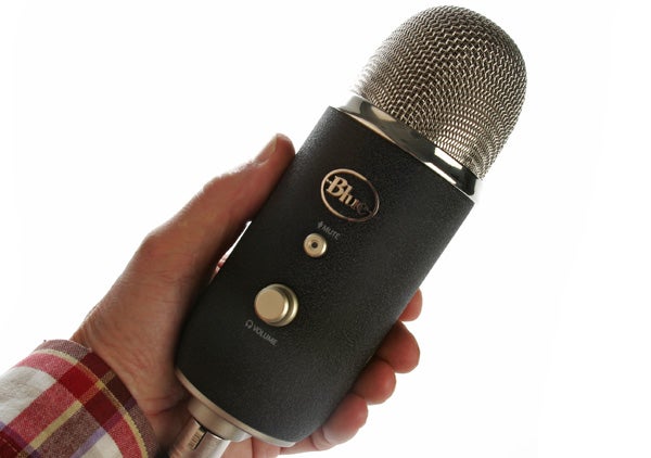 Hand holding a Blue Yeti Pro microphone against white background.