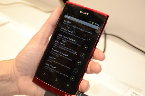 Hand holding Sony NWZ-Z1000 displaying sound settings menu.