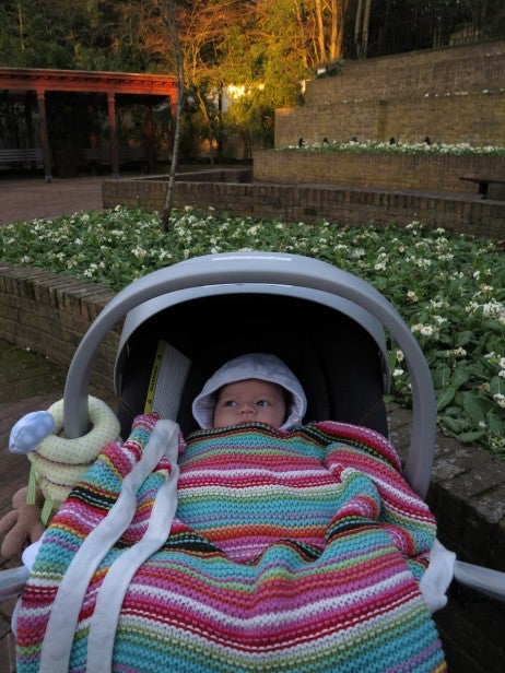 Baby in stroller with colorful blanket outdoors