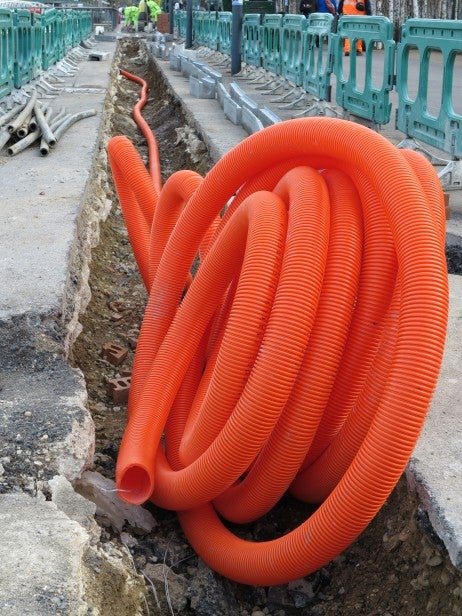 Coiled orange construction tubing in a trench.