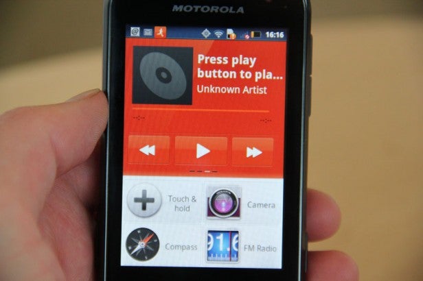 Motorola Defy Mini smartphone displaying its music player app.Hand holding a Motorola Defy Mini showing weather forecast.