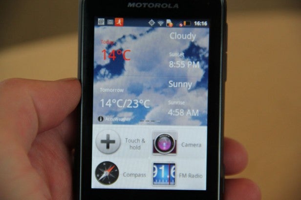 Hand holding a Motorola Defy Mini showing weather forecast.
