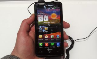 Hand holding an LG Spectrum smartphone with screen on.