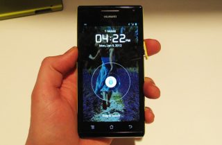 Hand holding Huawei Ascend P1 S smartphone displaying lock screen.