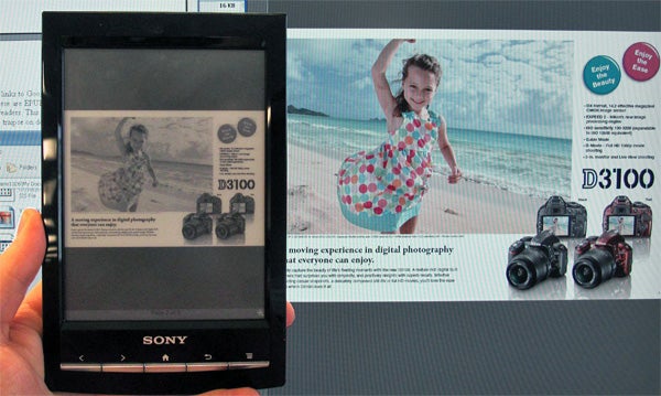 Sony Reader PRS-T1 on wooden surface displaying a webpage.Sony Reader PRS-T1 held in front of a camera advertisement.Sony Reader PRS-T1 displaying hand-written note on screen.Sony Reader PRS-T1 displaying a music player application.Hand holding Sony Reader PRS-T1 displaying menu screen.