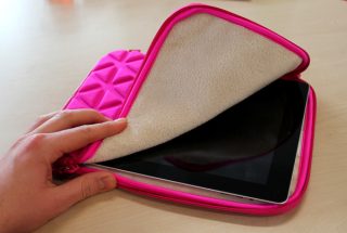 Hand opening a pink iLuv neoprene iPad case with iPad inside.