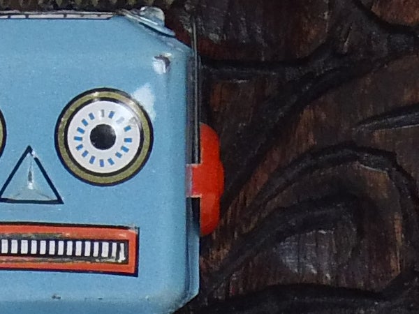 Close-up of a vintage blue toy robot against a wooden background.