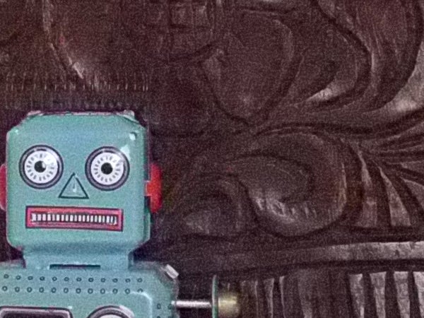 Vintage toy robot in front of carved wooden background