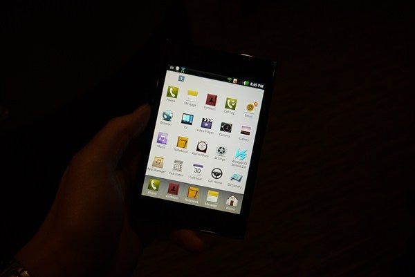 Hand holding LG Optimus Vu displaying apps on screen.