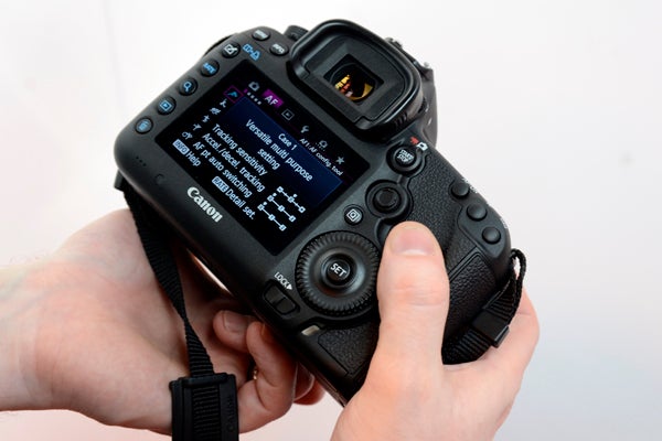 Hand holding Canon EOS 5D Mark III showing menu screen.